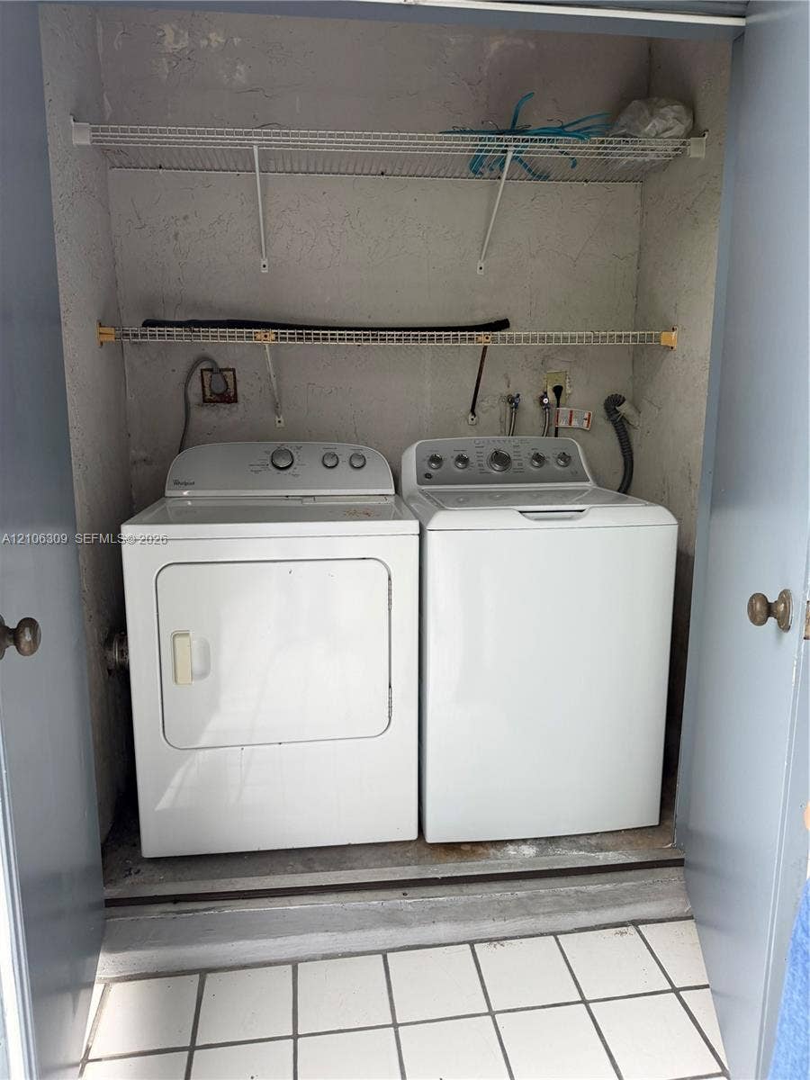8888 SW 131st Court, #409, Miami, FL 33186 Laundry closet featuring white tile flooring and dual integrated wire shelving units