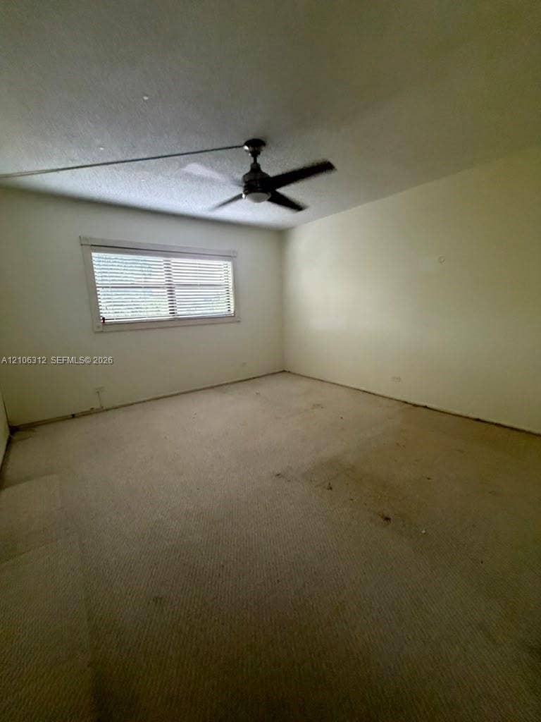 Interior room featuring carpeted flooring, a ceiling fan with integrated lighting, and a horizontal window with blinds