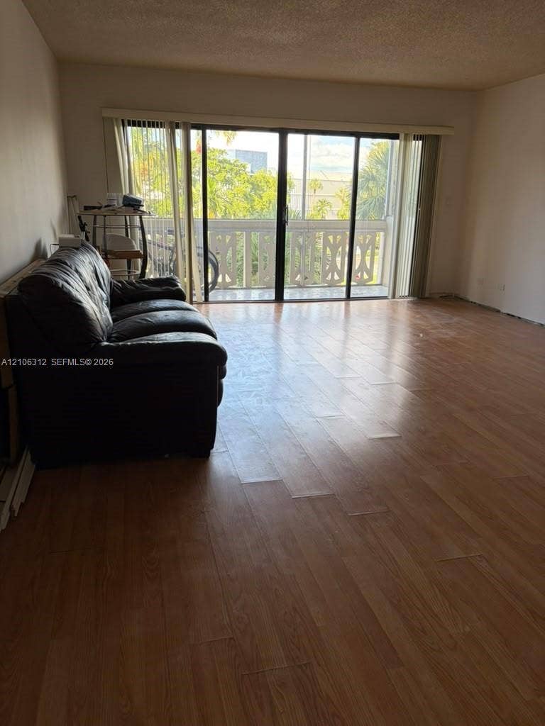 800 NE 195th Street, #311, Miami, Miami, FL 33179 Living area featuring wood-finish flooring and large sliding glass doors opening to a balcony with decorative geometric railings