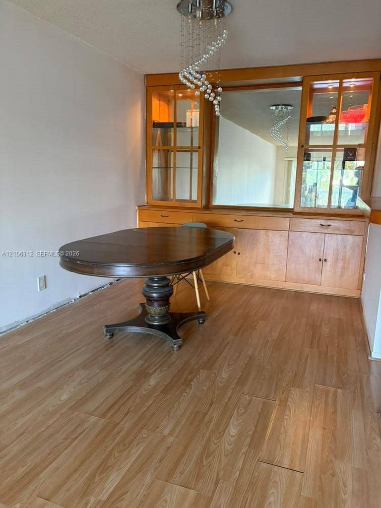 800 NE 195th Street, #311, Miami, Miami, FL 33179 Built-in wooden cabinetry featuring glass-front display sections, a central mirror, and integrated storage, accented by a contemporary spiral crystal chandelier and wood-finish flooring