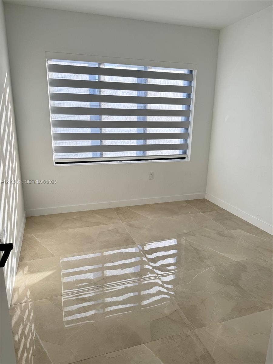 14508 SW 260th Street, #14508, Homestead, Homestead, FL 33032 Room featuring polished large-format tile flooring, neutral wall finishes, and a window equipped with horizontal zebra-style blinds