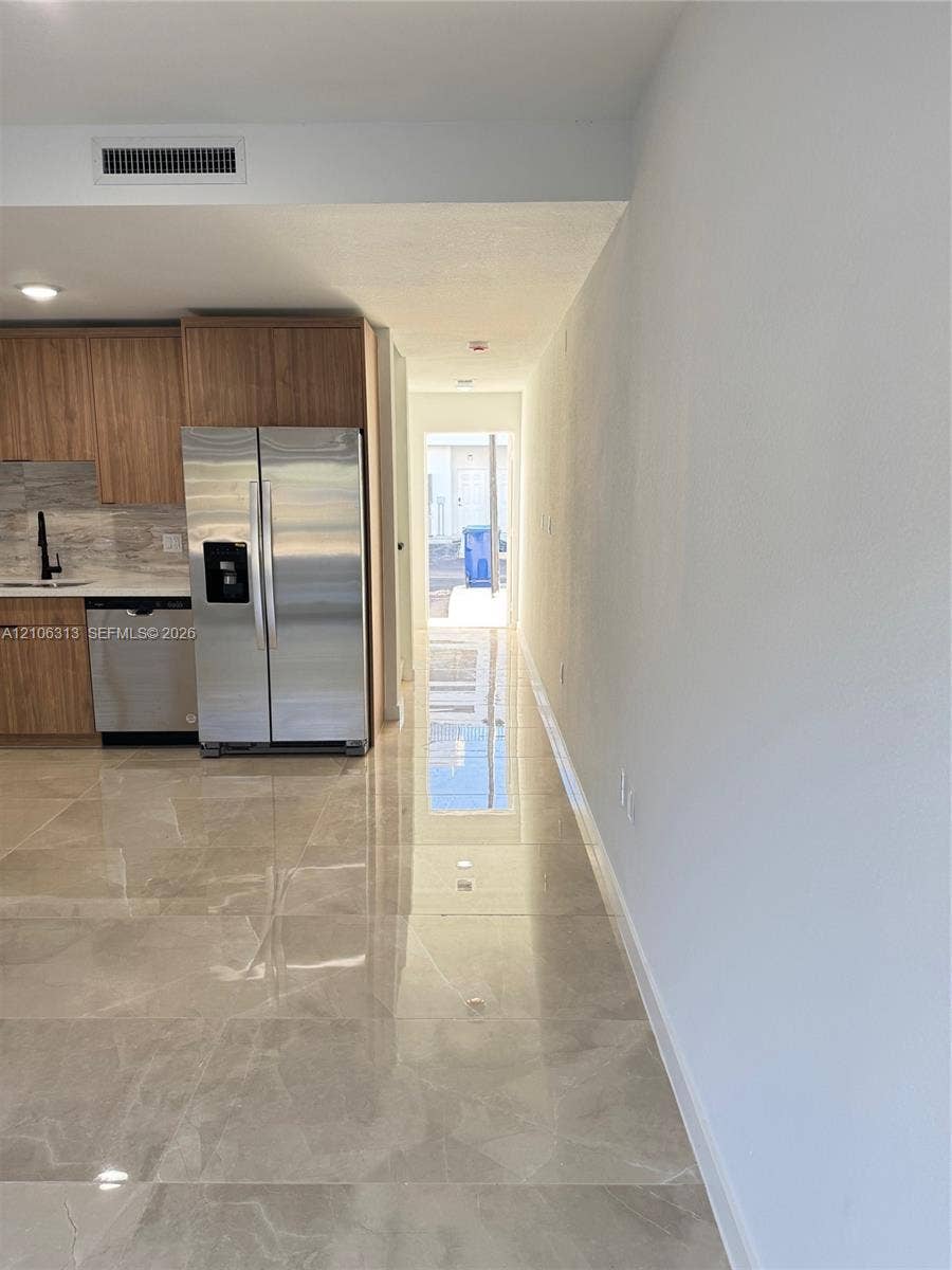 14508 SW 260th Street, #14508, Homestead, Homestead, FL 33032 Kitchen area featuring light wood-finish cabinetry, stainless steel appliances, a stone-finish tile floor, and a stone-finish backsplash