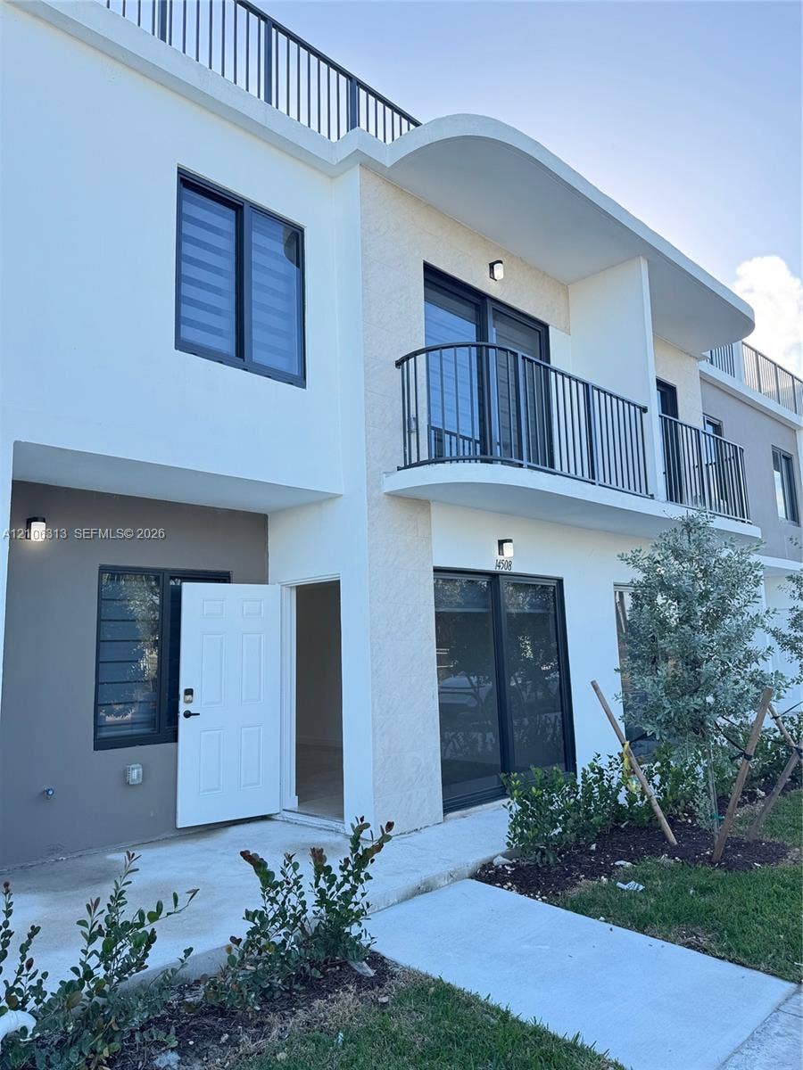 14508 SW 260th Street, #14508, Homestead, Homestead, FL 33032 Contemporary two-story exterior featuring smooth stucco siding, a curved architectural roofline, metal balcony railings, and a rooftop terrace