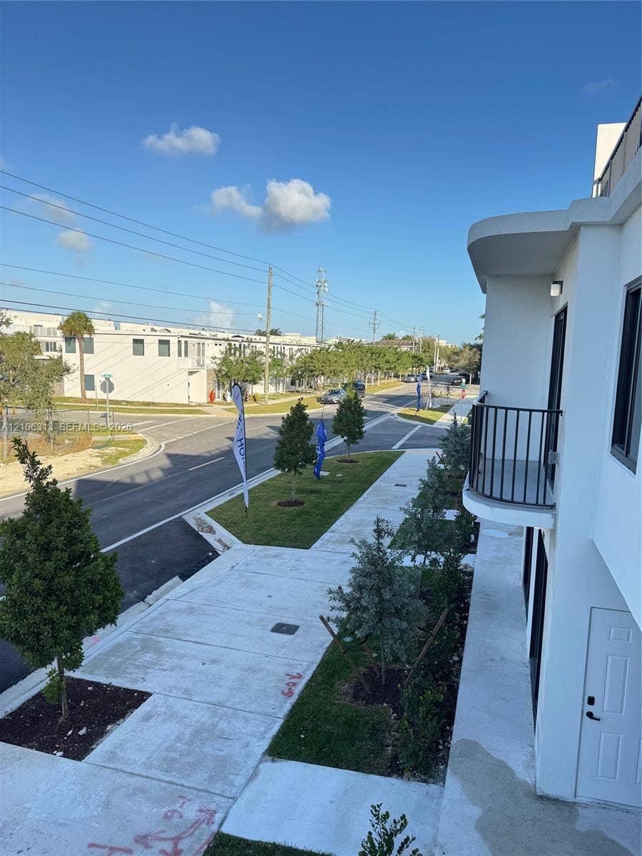 14508 SW 260th Street, #14508, Homestead, Homestead, FL 33032 Modern exterior architecture featuring a curved balcony with metal railing, white smooth-stucco finish, and integrated wall lighting