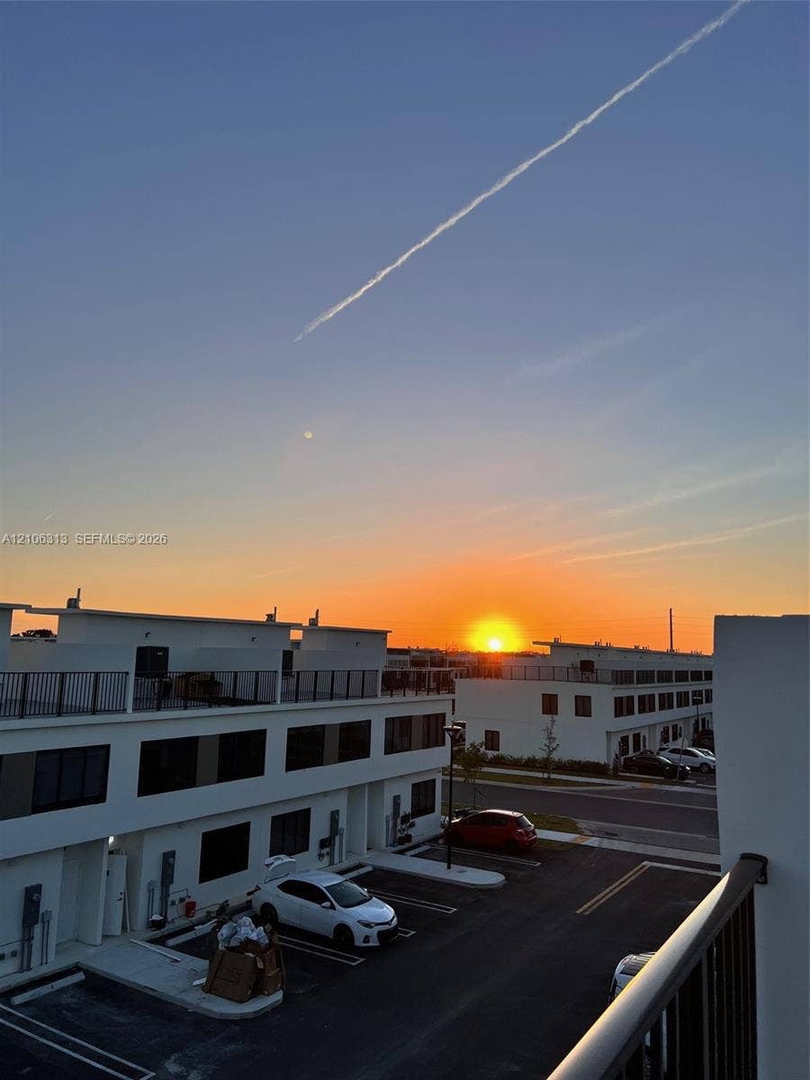 14508 SW 260th Street, #14508, Homestead, Homestead, FL 33032 Modern multi-level exterior with rooftop terraces, white stucco facade, and black metal railings, featuring sunset horizon