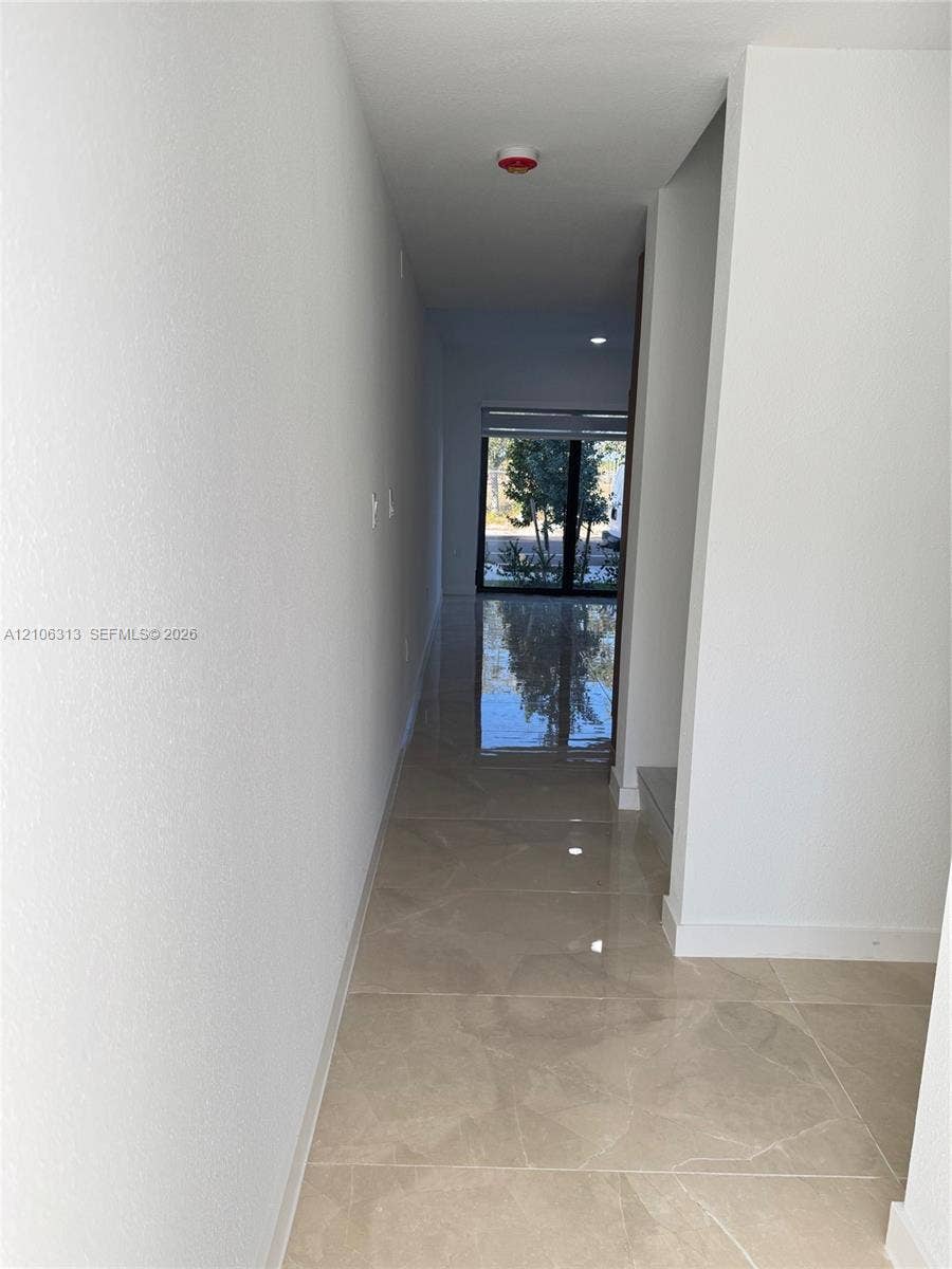 14508 SW 260th Street, #14508, Homestead, Homestead, FL 33032 Interior hallway featuring polished stone-finish tile flooring, recessed ceiling lighting, and large glass paneled exterior doors