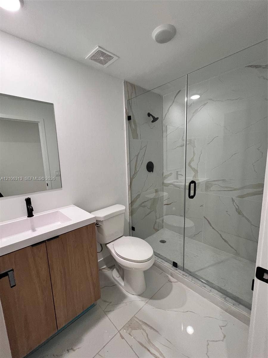 14508 SW 260th Street, #14508, Homestead, Homestead, FL 33032 Modern bathroom featuring a wood-finish vanity with a rectangular sink, matte black hardware, frameless glass-enclosed shower with floor-to-ceiling tile, and large-format porcelain tile flooring
