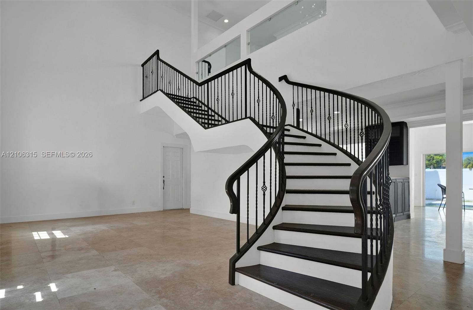 2319 NE 35th Drive, Fort Lauderdale, FL 33308 Curved staircase with iron balusters, high ceilings, stone flooring, and built-in cabinetry