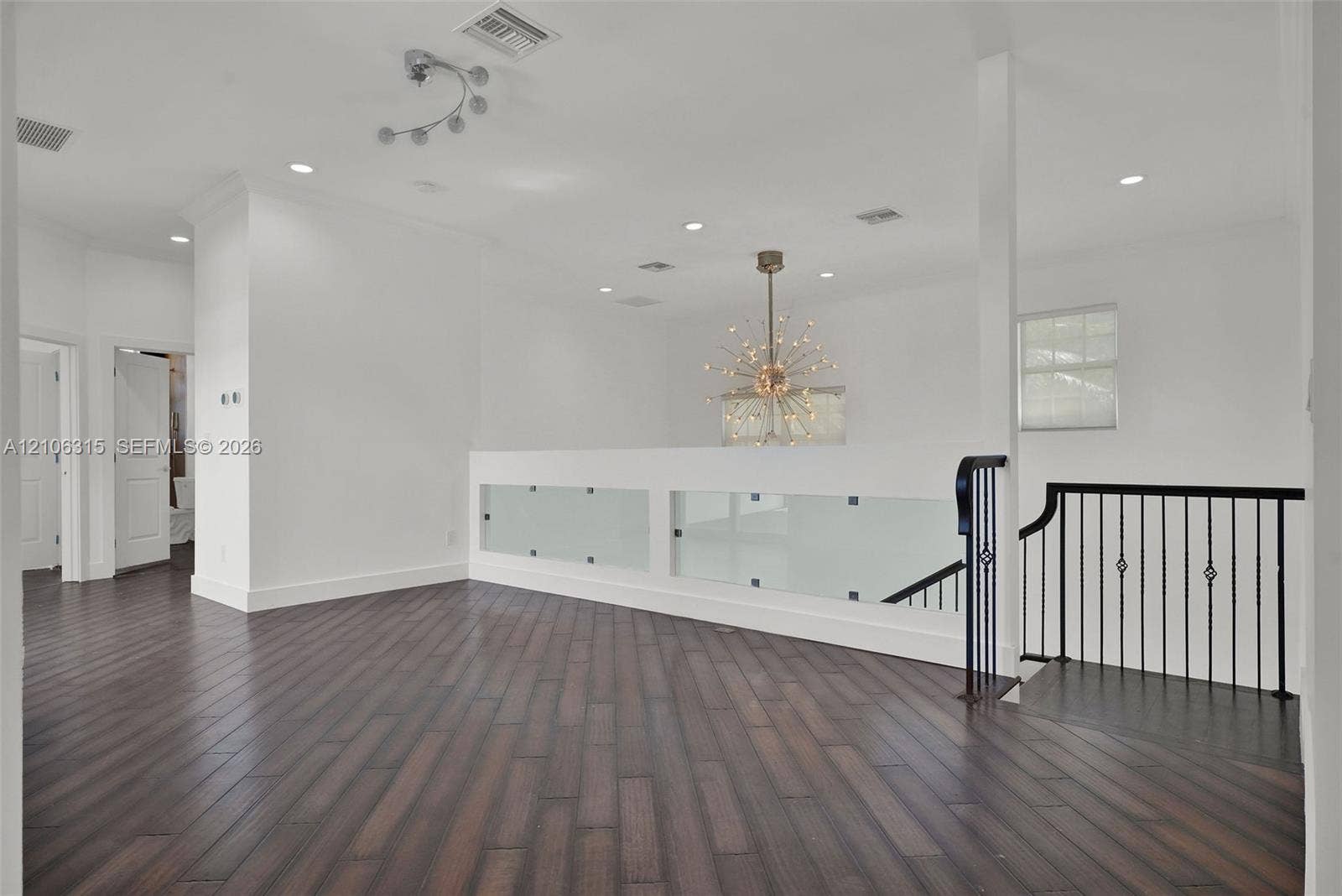 2319 NE 35th Drive, Fort Lauderdale, FL 33308 Wood-finish flooring, matte black metal railings, frosted glass safety panels, starburst-style chandelier, and recessed lighting