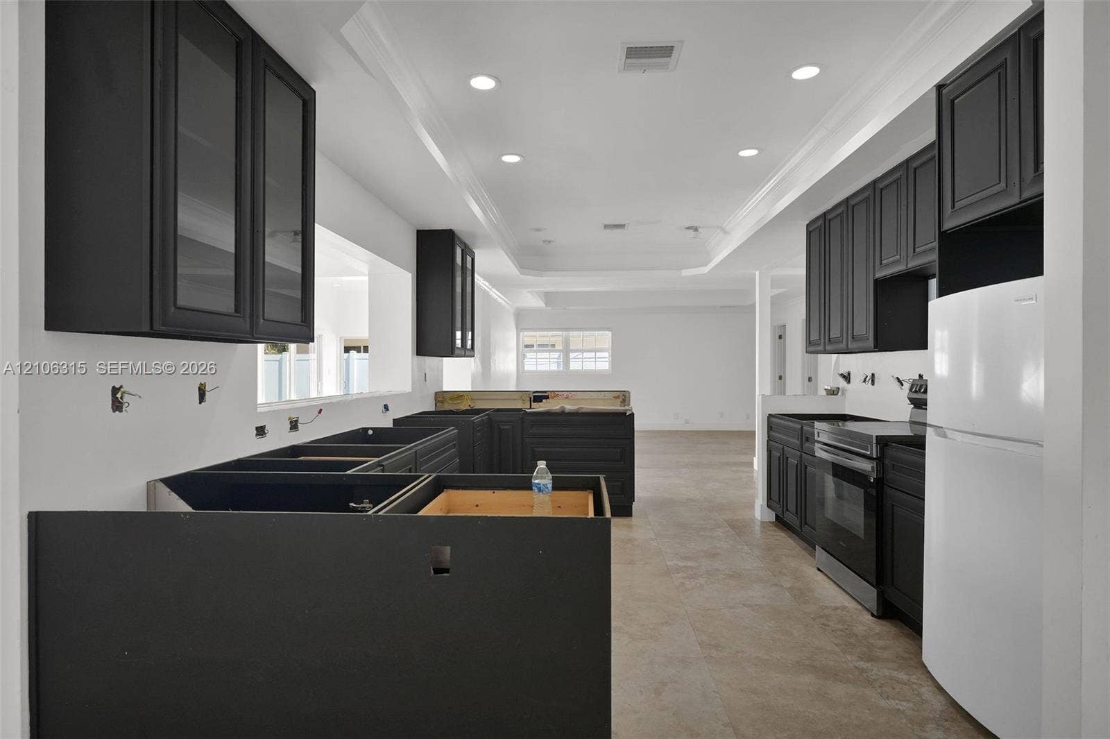 2319 NE 35th Drive, Fort Lauderdale, FL 33308 Kitchen featuring dark-toned shaker-style cabinetry, stone flooring, recessed lighting, and crown molding