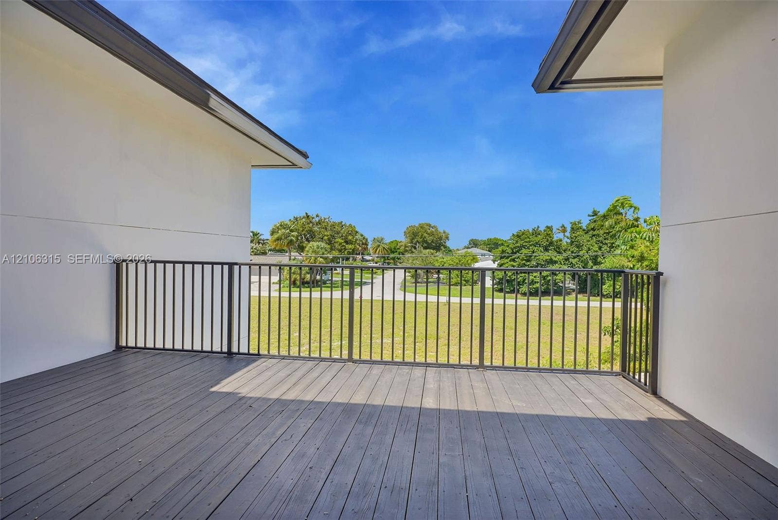 2319 NE 35th Drive, Fort Lauderdale, FL 33308 Covered outdoor deck featuring wood-finish decking, dark metal railings, and neutral exterior walls