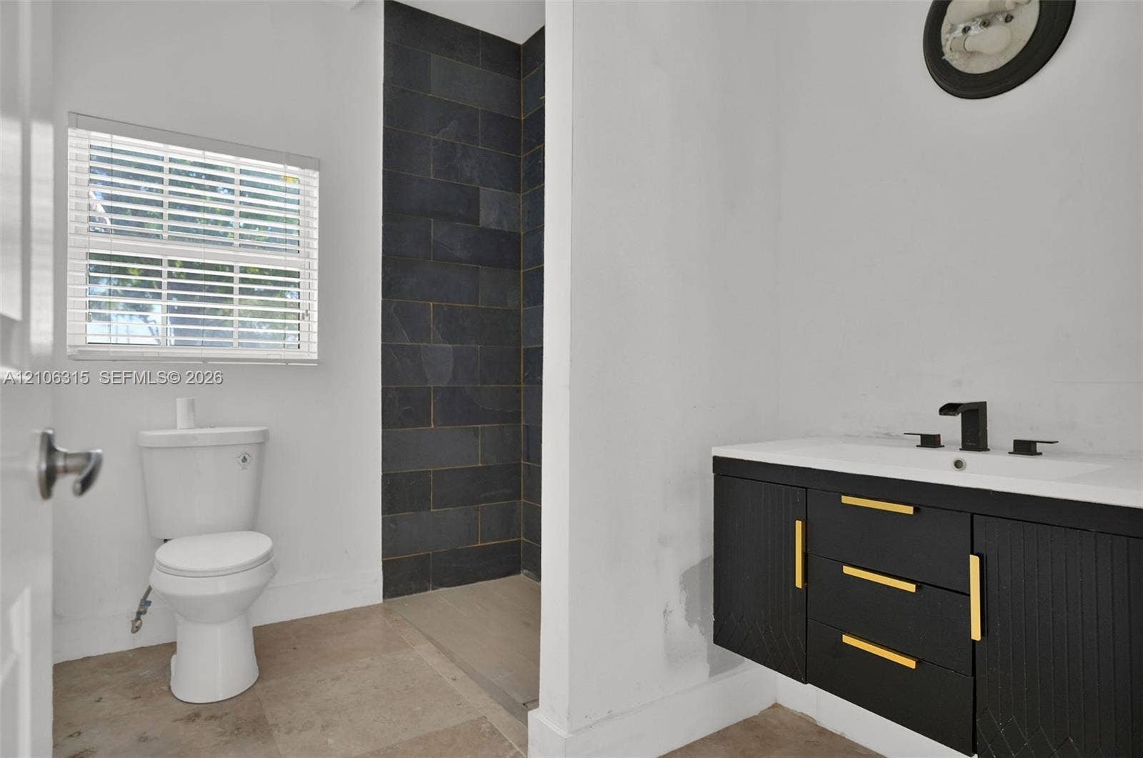 2319 NE 35th Drive, Fort Lauderdale, FL 33308 Bathroom featuring a floating vanity with black cabinetry, gold-tone hardware, and a white countertop