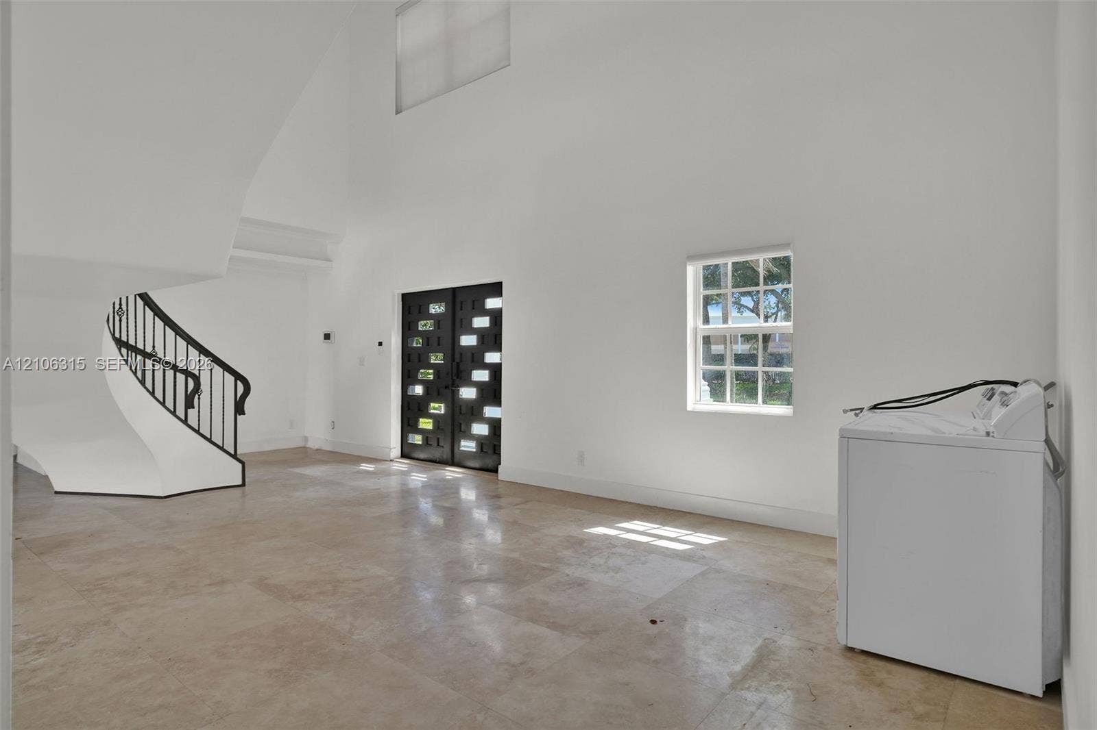 2319 NE 35th Drive, Fort Lauderdale, FL 33308 Double-height foyer featuring stone tile flooring, a curved staircase with a metal handrail, and a decorative double entry door with glass paneling