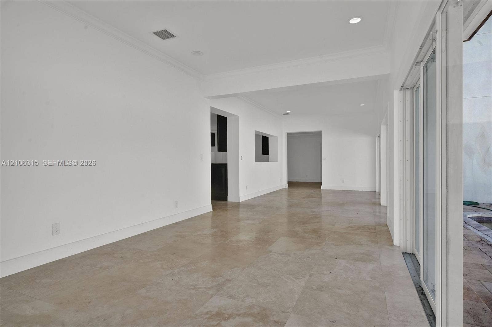 2319 NE 35th Drive, Fort Lauderdale, FL 33308 Neutral-toned large-format tile flooring, recessed ceiling lighting, and expansive multi-panel sliding glass door system