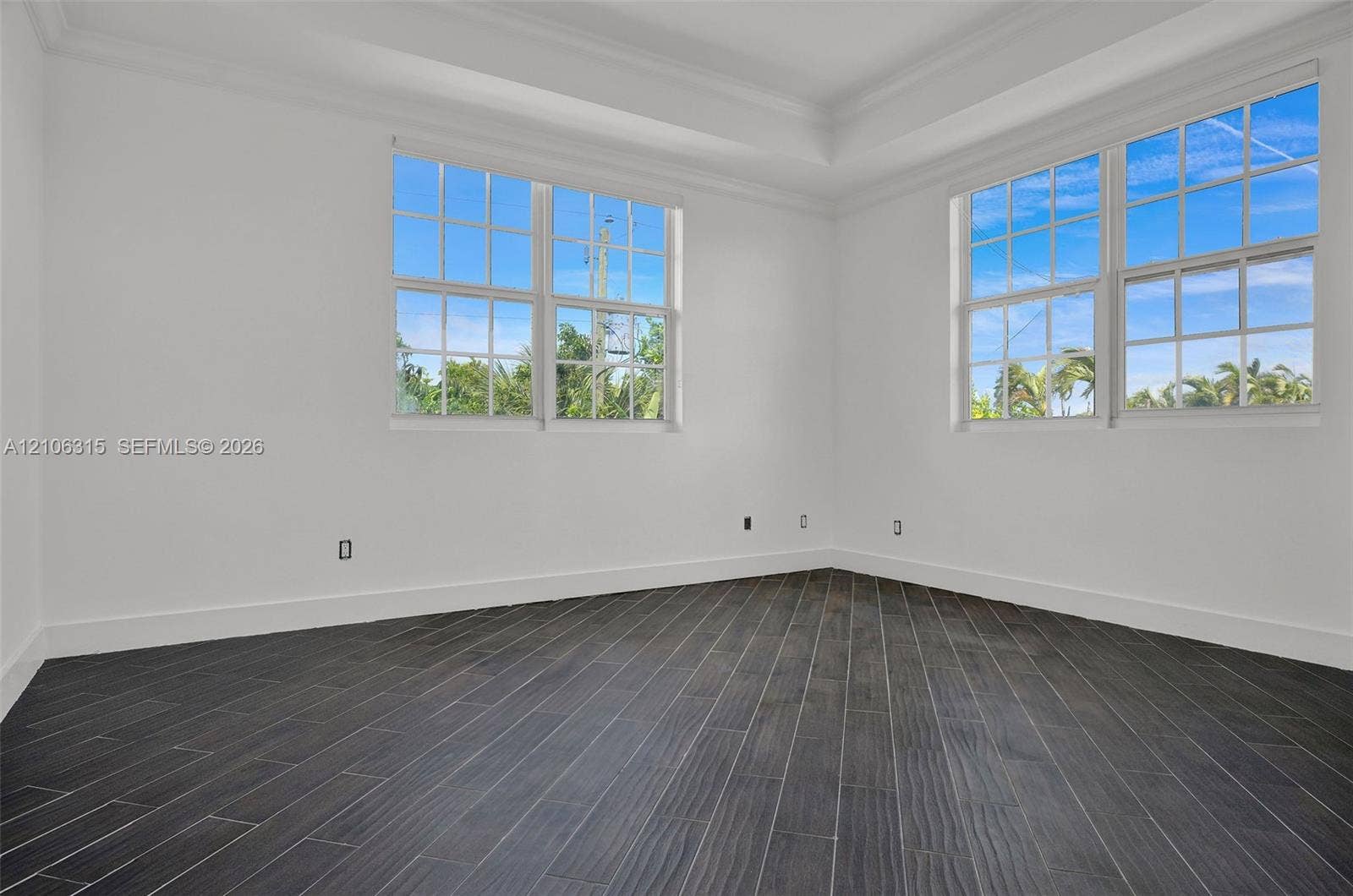 2319 NE 35th Drive, Fort Lauderdale, FL 33308 Room featuring dark wood-finish flooring in a herringbone pattern, a tray ceiling, and multi-pane windows