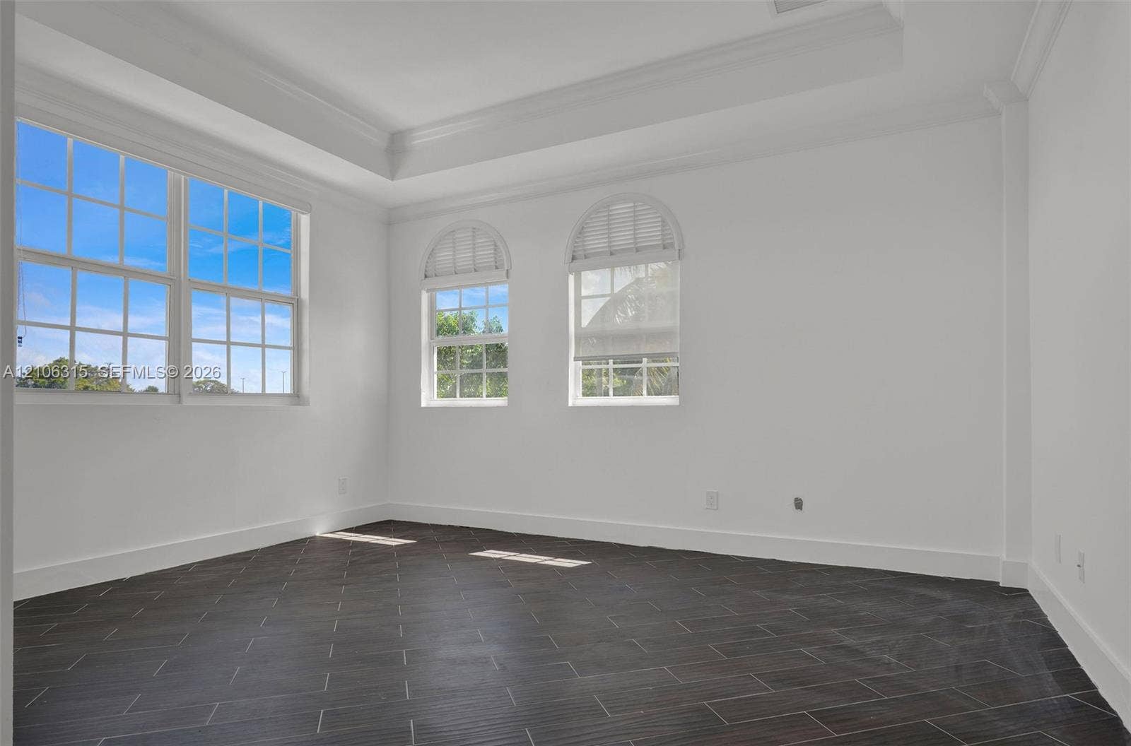 2319 NE 35th Drive, Fort Lauderdale, FL 33308 Room featuring dark tile flooring, a tray ceiling, and windows with arched upper panes