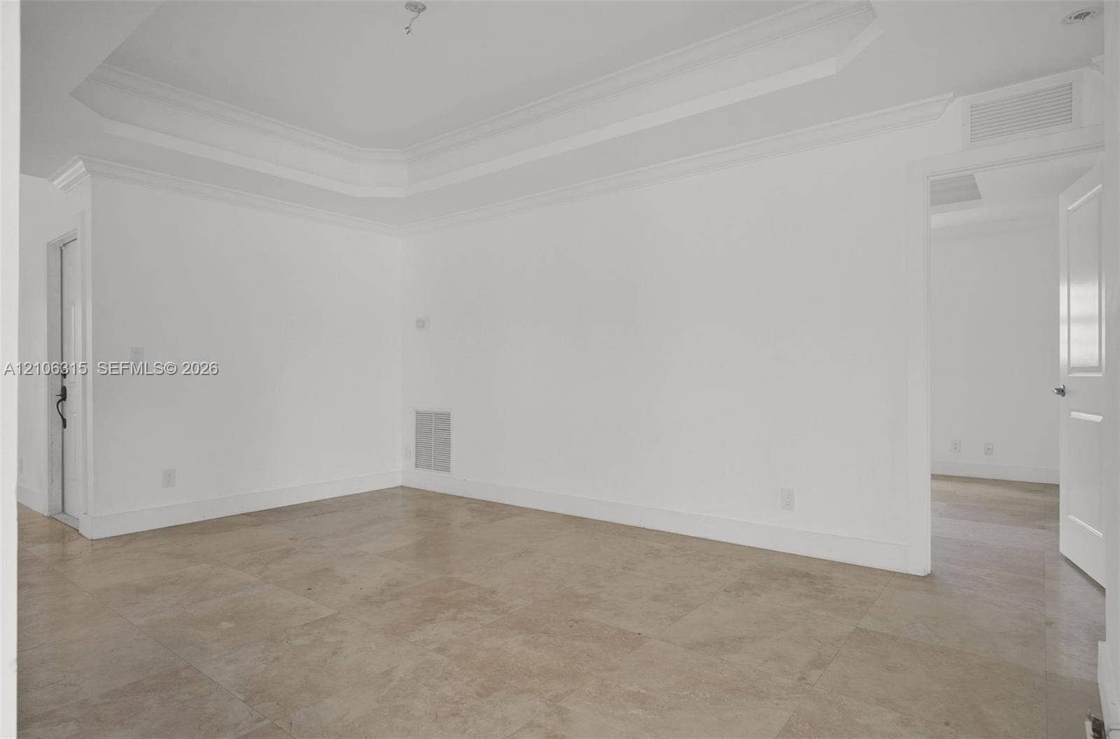 2319 NE 35th Drive, Fort Lauderdale, FL 33308 Interior space featuring a recessed tray ceiling, crown molding, and large-format neutral tile flooring