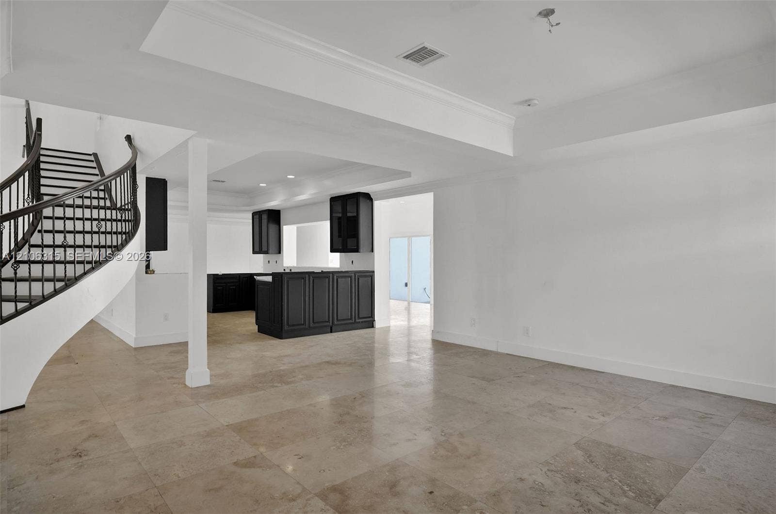2319 NE 35th Drive, Fort Lauderdale, FL 33308 Curved staircase with iron balusters, stone-finish flooring, recessed tray ceilings, and built-in dark cabinetry
