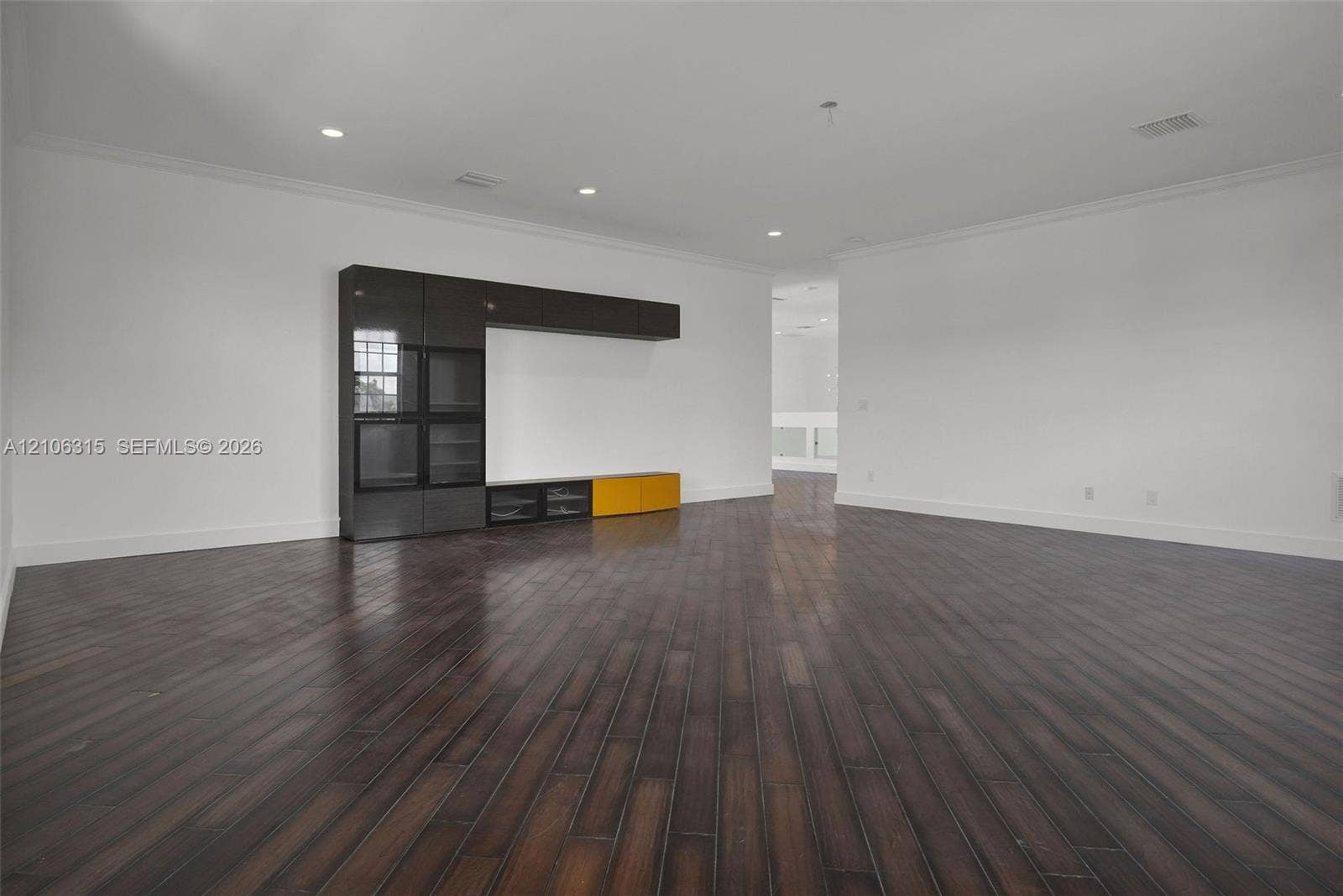 2319 NE 35th Drive, Fort Lauderdale, FL 33308 Spacious interior featuring dark wood-finish flooring, recessed lighting, crown molding, and built-in cabinetry with glass-front storage