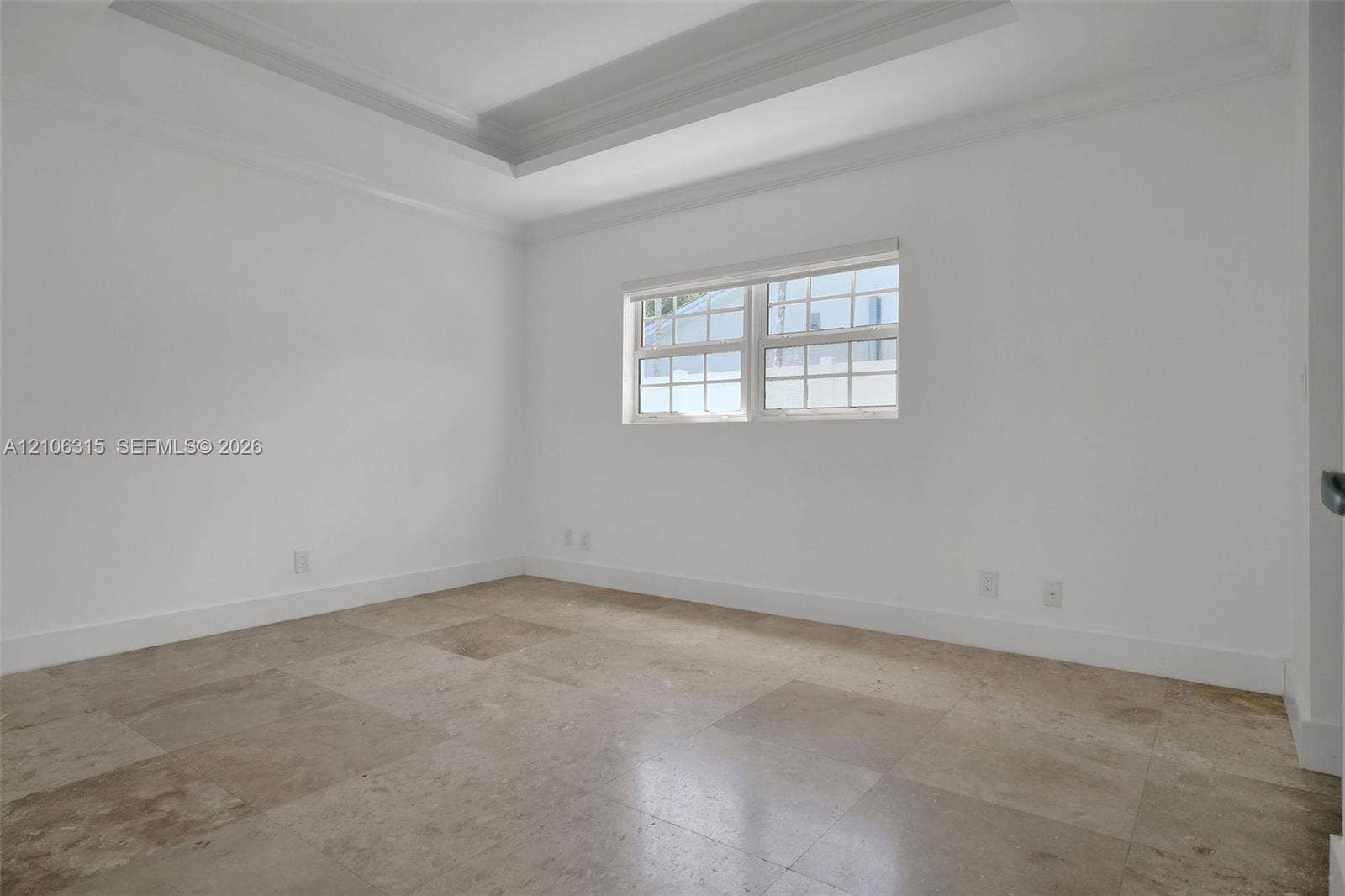 2319 NE 35th Drive, Fort Lauderdale, FL 33308 Room featuring a tray ceiling, natural stone tile flooring, and a multi-pane window with a horizontal blind