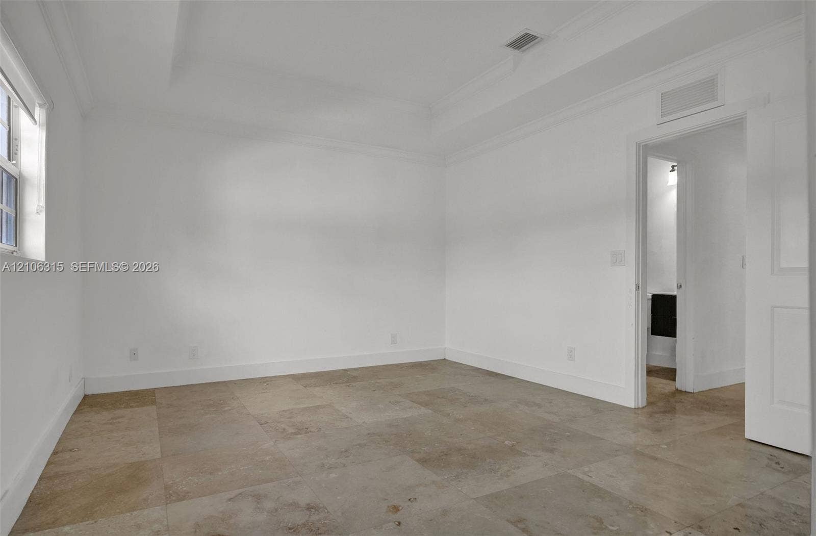 2319 NE 35th Drive, Fort Lauderdale, FL 33308 Neutral-toned tile flooring, recessed tray ceiling with crown molding, and a multi-panel door