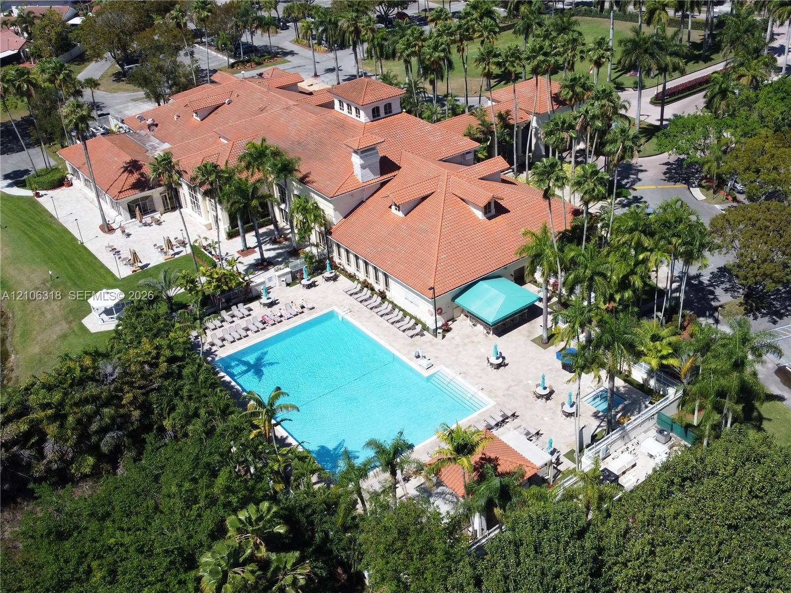 9921 NW 51st Lane, Doral, FL 33178 Doral Country Club with a large swimming pool with surrounding stone patio, built-in poolside shelter, and mature palm trees