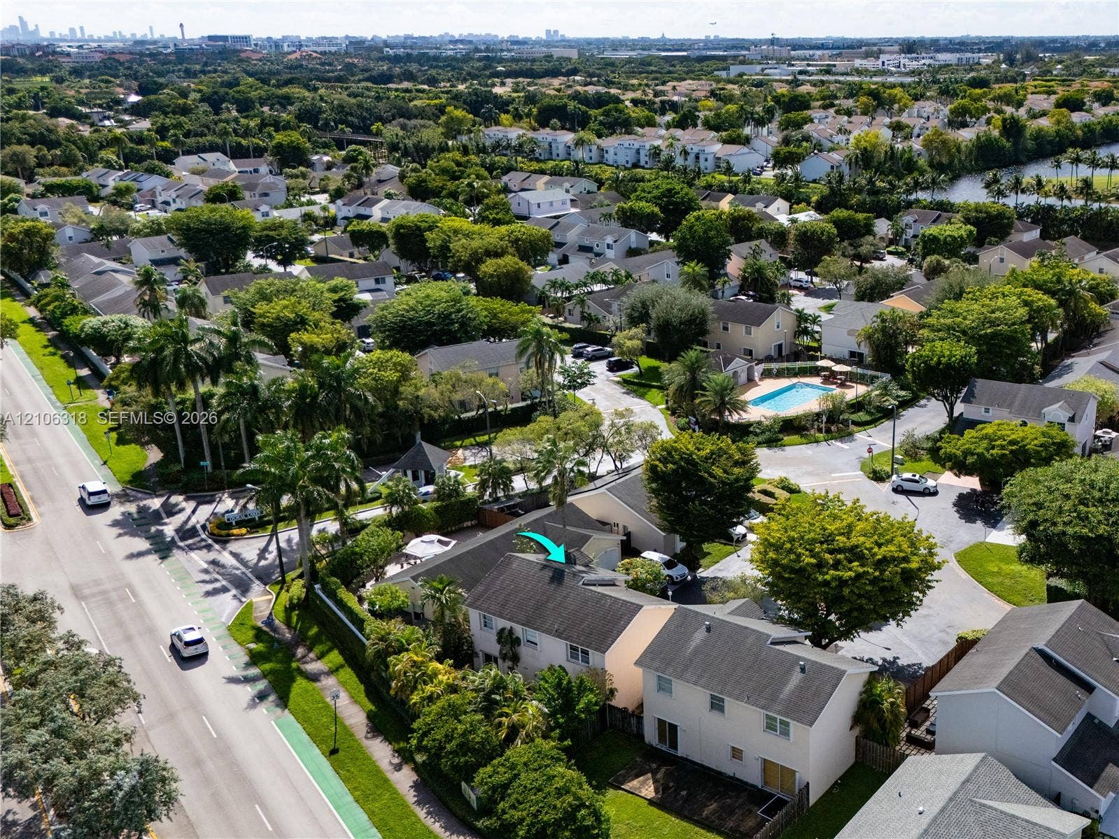 9921 NW 51st Lane, Doral, FL 33178 Aerial perspective of a multi-story residence featuring a shingled roof, light-toned exterior siding, mature landscaping, and an integrated private parking area