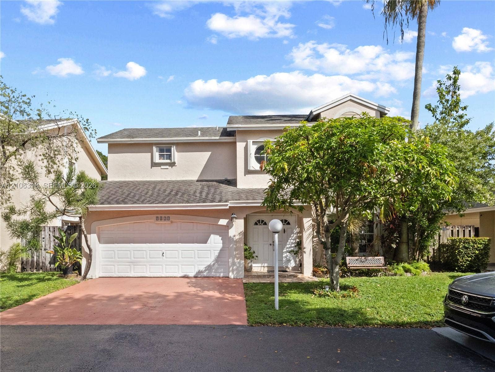9921 NW 51st Lane, Doral, FL 33178 Two-story residence featuring a stucco exterior, attached two-car garage, recessed entryway, and arched architectural details