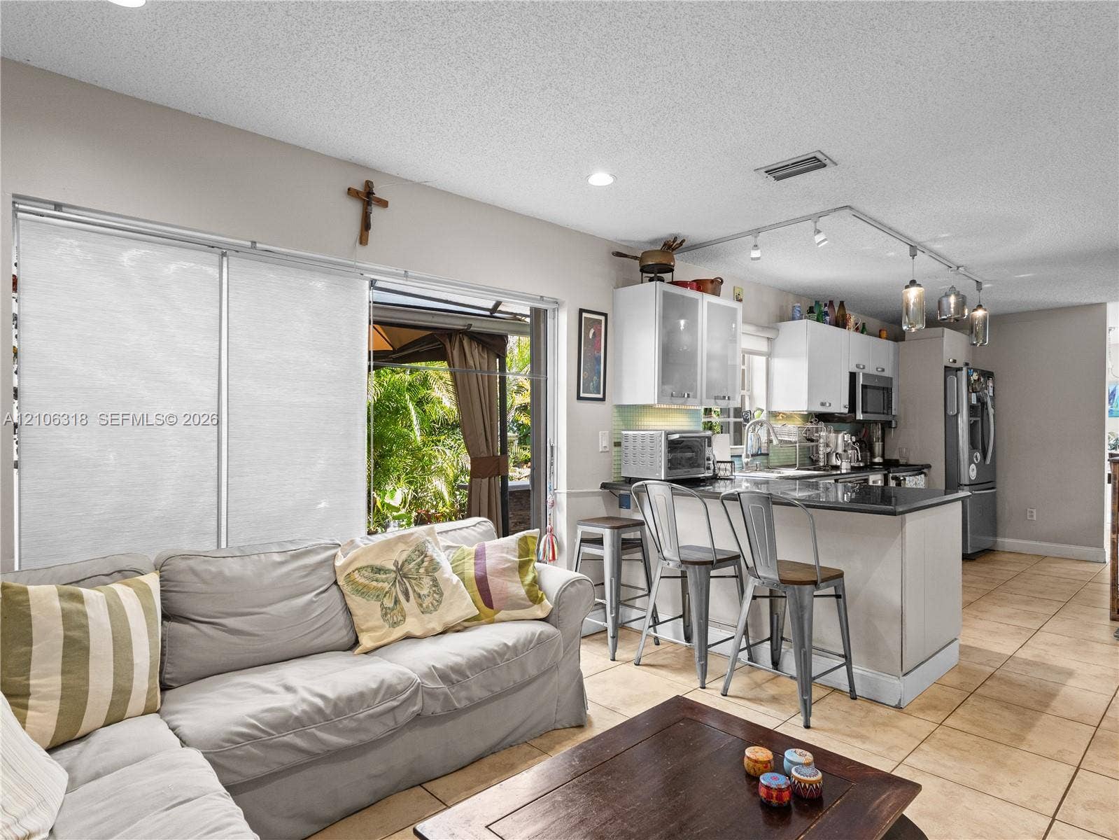9921 NW 51st Lane, Doral, FL 33178 Open-concept kitchen featuring white cabinetry, a dark stone countertop peninsula, track lighting, and ceramic tile flooring