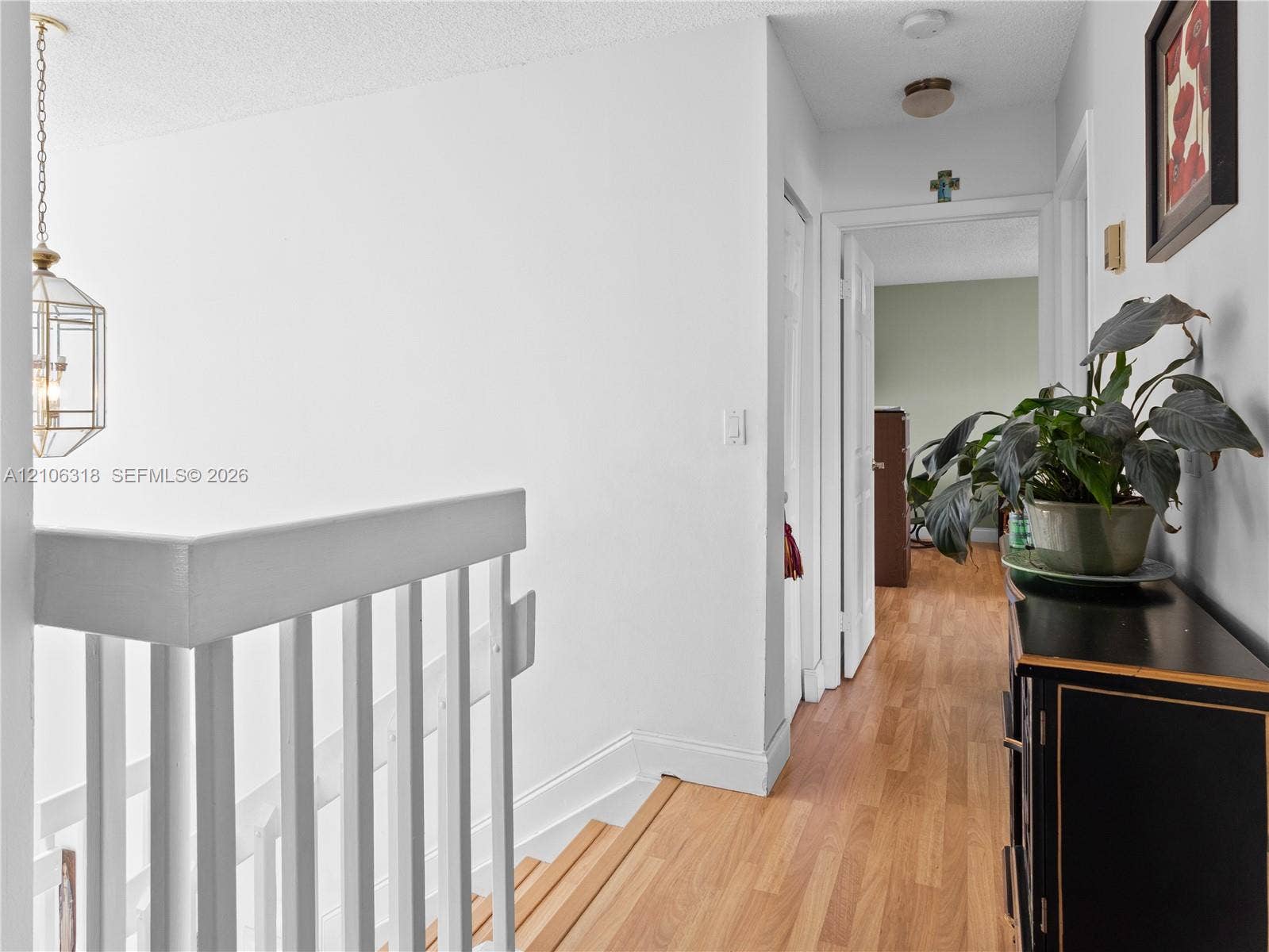 9921 NW 51st Lane, Doral, FL 33178 Hallway featuring wood-finish flooring, white staircase railing, and a geometric pendant light fixture