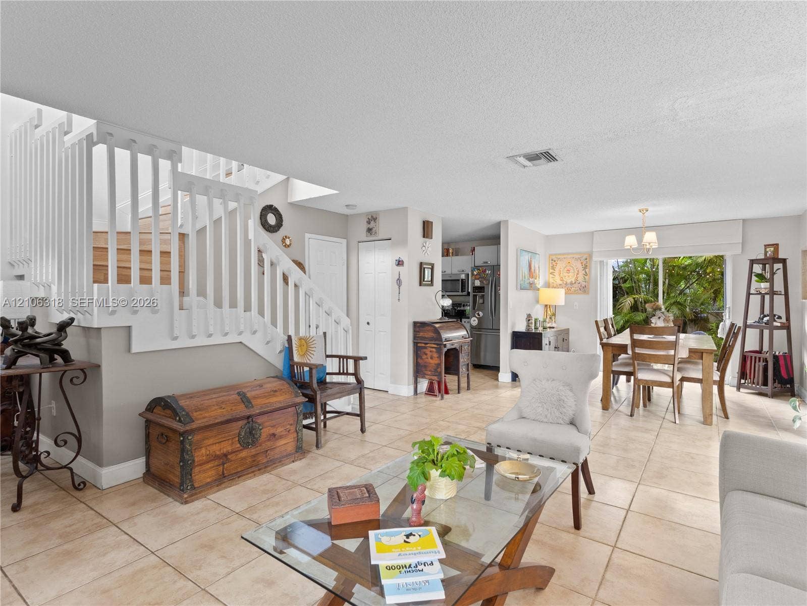 9921 NW 51st Lane, Doral, FL 33178 Open-concept interior featuring large-format tile flooring, a staircase with white balusters, and sliding glass doors with exterior access