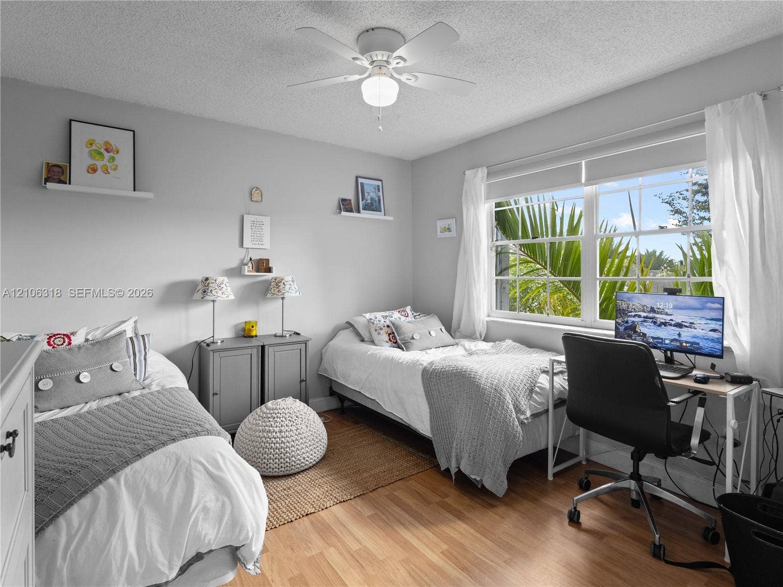 9921 NW 51st Lane, Doral, FL 33178 Wood-finish flooring, ceiling fan with integrated lighting, and multi-pane window with natural exterior foliage