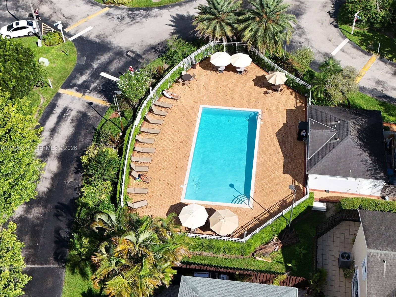 9921 NW 51st Lane, Doral, FL 33178 Community swimming pool featuring a rectangular basin, perimeter fencing, and an expansive paved deck