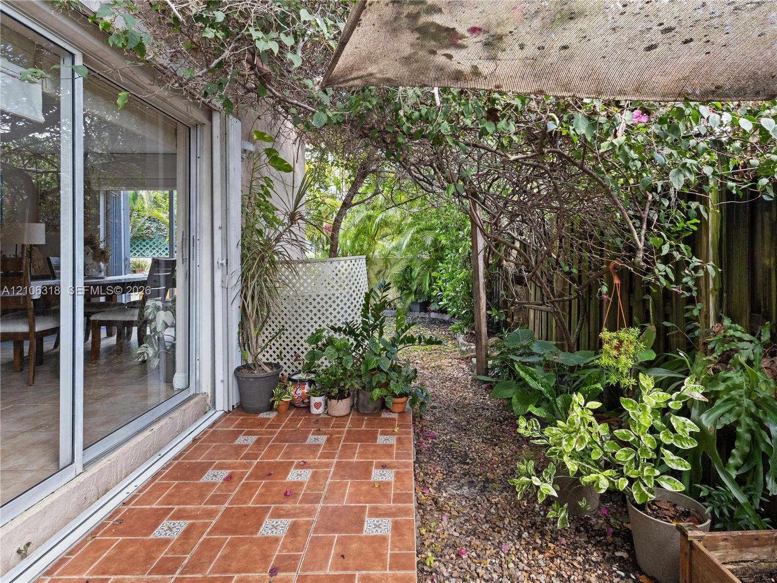 9921 NW 51st Lane, Doral, FL 33178 Outdoor patio featuring terracotta-style tile flooring, sliding glass door, and a lattice privacy screen