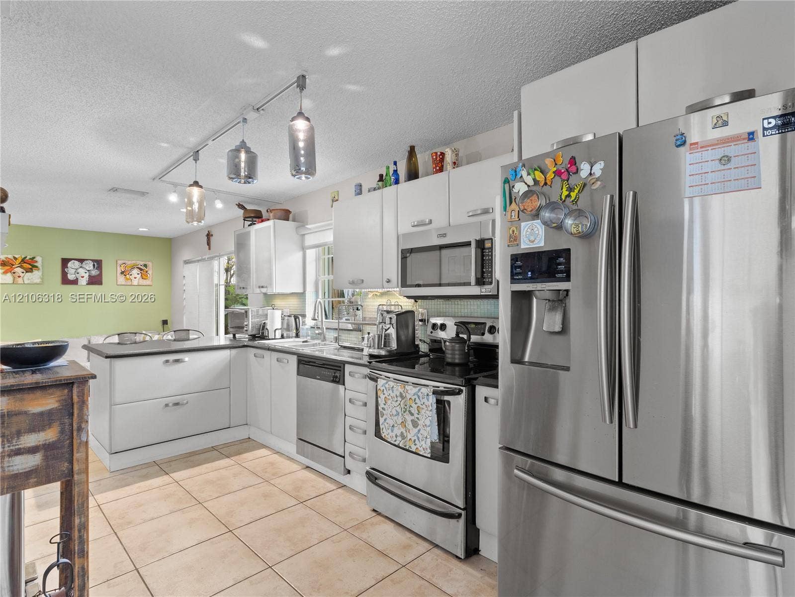 9921 NW 51st Lane, Doral, FL 33178 Kitchen featuring white cabinetry, stainless steel appliances, ceramic tile flooring, and adjustable track lighting