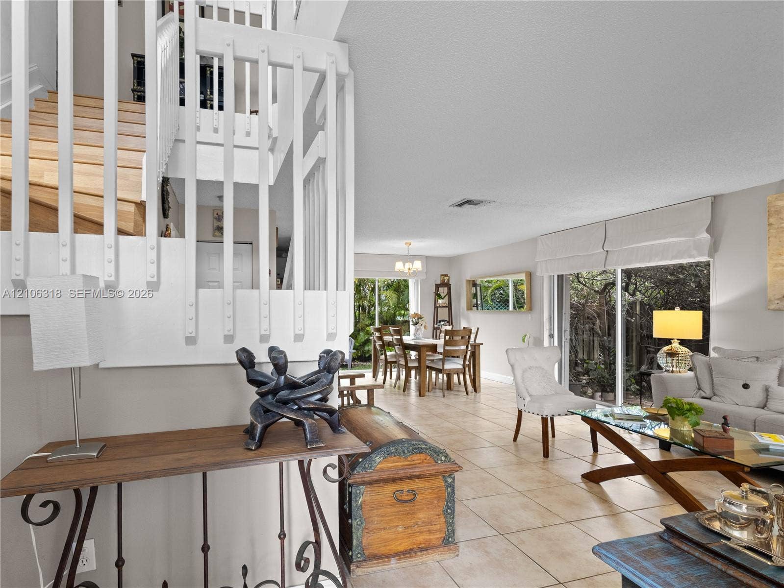 9921 NW 51st Lane, Doral, FL 33178 Open-concept interior featuring large-format tile flooring, a staircase with white vertical balusters and wood treads, and sliding glass doors