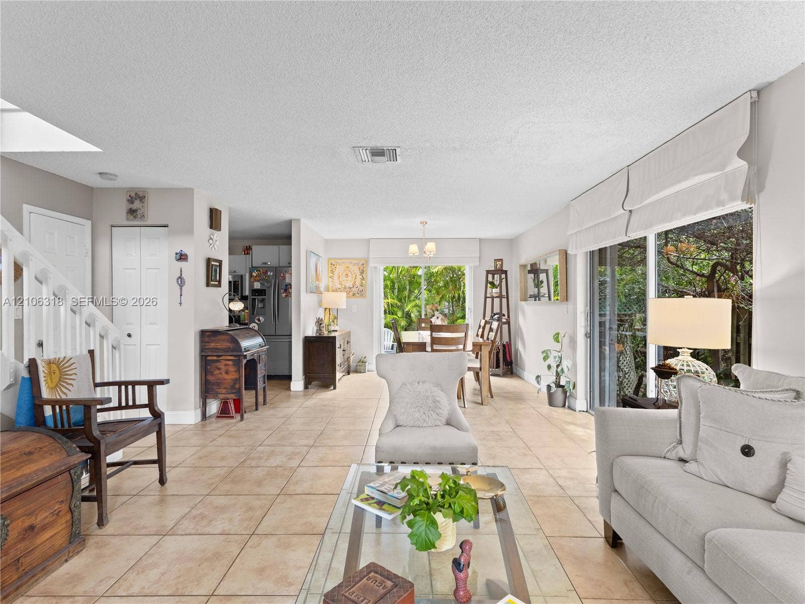 9921 NW 51st Lane, Doral, FL 33178 Open-concept interior featuring oversized tile flooring, sliding glass doors, built-in staircase railing, and neutral wall tones