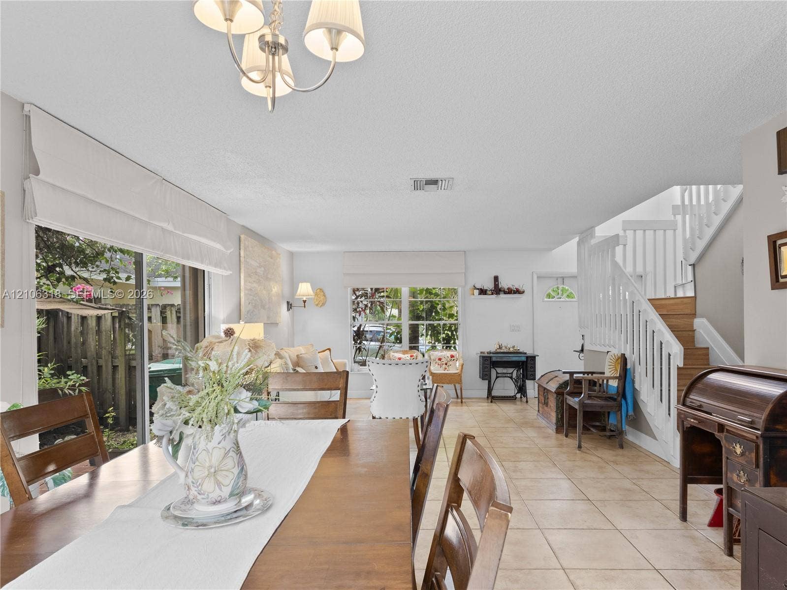 9921 NW 51st Lane, Doral, FL 33178 Open floor plan featuring tile flooring, multi-pane windows, sliding glass doors, a decorative chandelier.