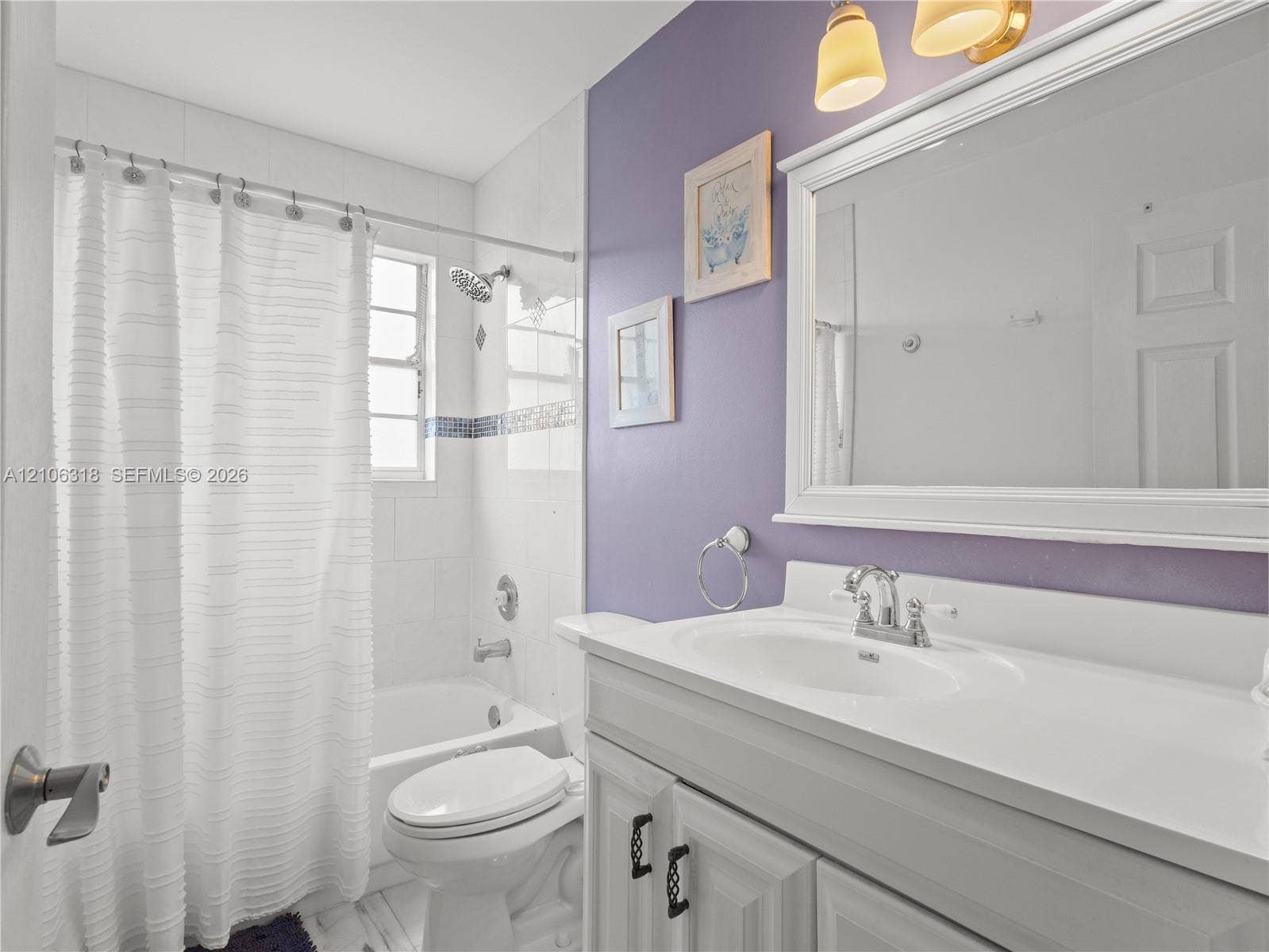 9921 NW 51st Lane, Doral, FL 33178 Bathroom featuring a white vanity cabinet with an integrated sink, a large framed wall-mounted mirror, a tiled shower and tub combination, and brushed-finish metal fixtures