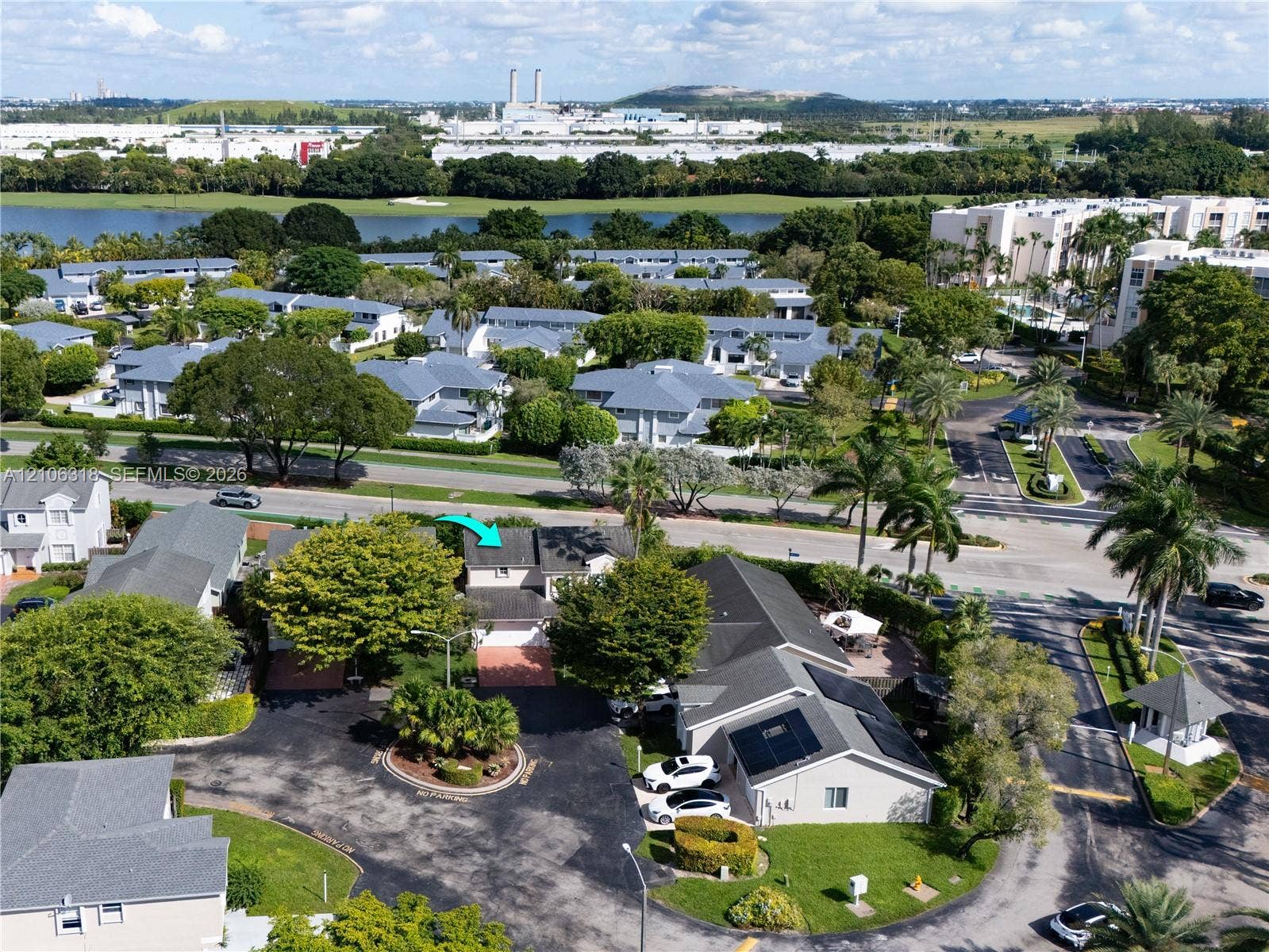 9921 NW 51st Lane, Doral, FL 33178 Aerial perspective of a multi-story residence featuring a shingled roof, attached garage, and paved driveway situated within a landscaped community