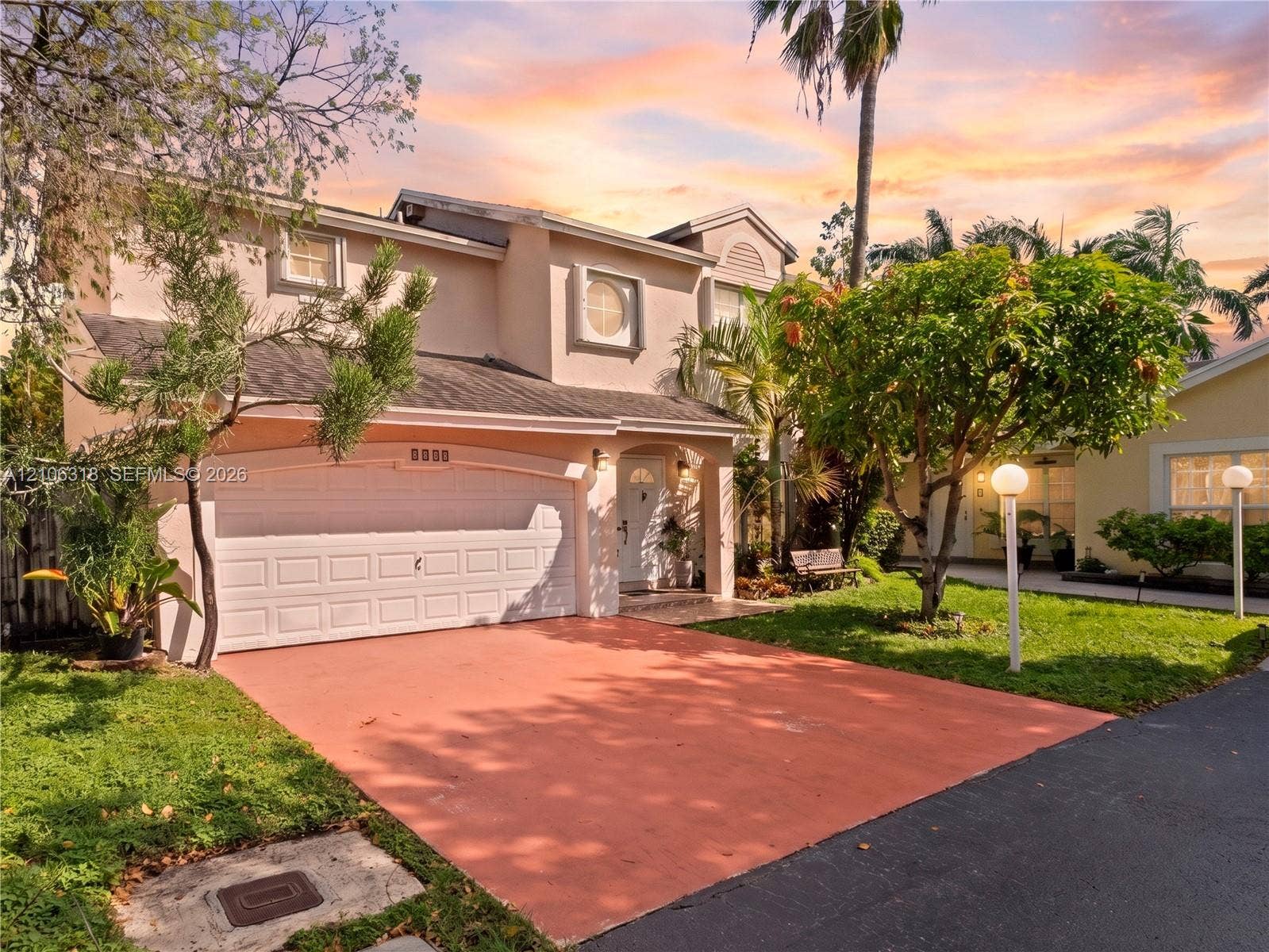 9921 NW 51st Lane, Doral, FL 33178 Two-story exterior featuring a stucco facade, an arched entryway, a double-car garage, and a paved driveway