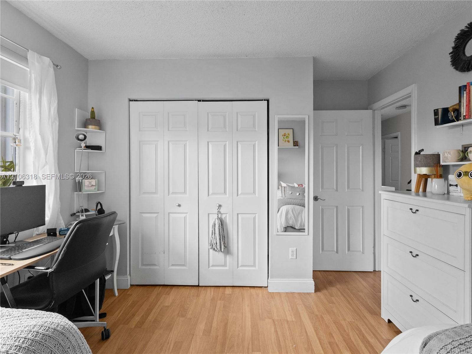 9921 NW 51st Lane, Doral, FL 33178 Wood-finish flooring, white paneled doors, and a wall-mounted mirror
