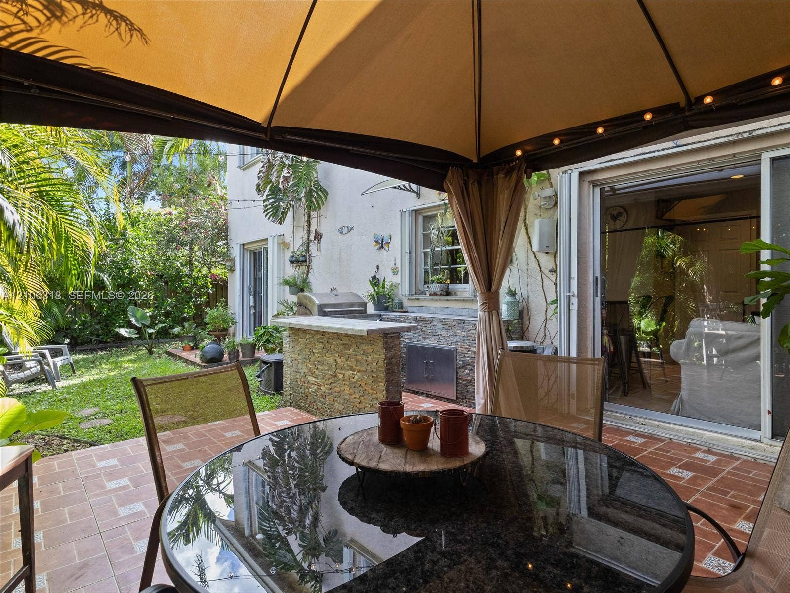 9921 NW 51st Lane, Doral, FL 33178 Outdoor living space featuring a built-in outdoor kitchen with stone veneer, stainless steel grill, tile patio flooring, and a permanent gazebo structure