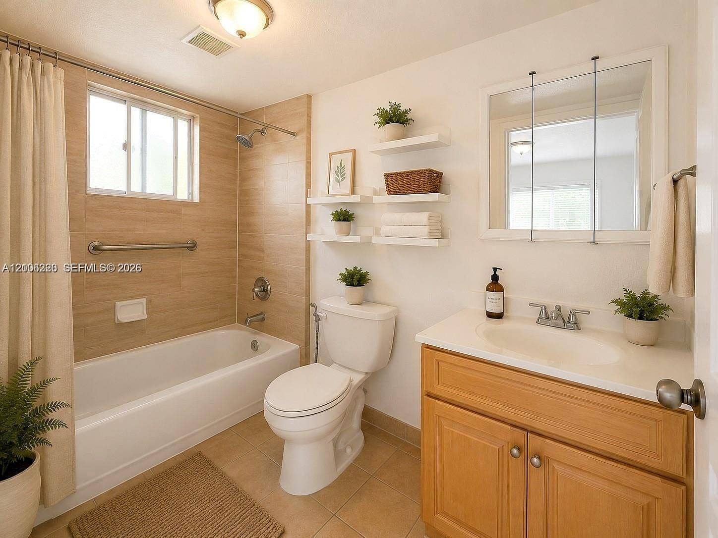 Bathroom featuring a tub-shower combination with floor-to-ceiling tile surround, vanity with an integrated basin, medicine cabinet with mirrored doors, and floating wall-mounted shelving