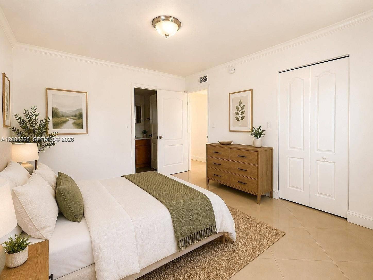 Neutral interior space featuring polished tile flooring, crisp white walls, crown molding, a central flush-mount ceiling fixture, and a white bi-fold closet door