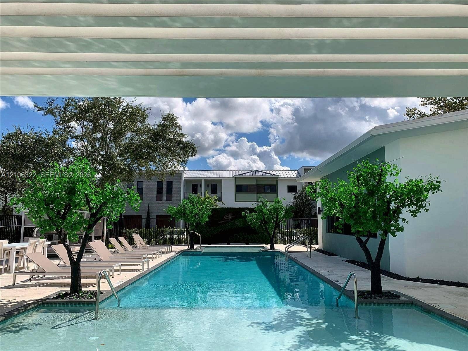 Rectangular swimming pool featuring a stone-paver deck, built-in metal handrails, and integrated landscaping