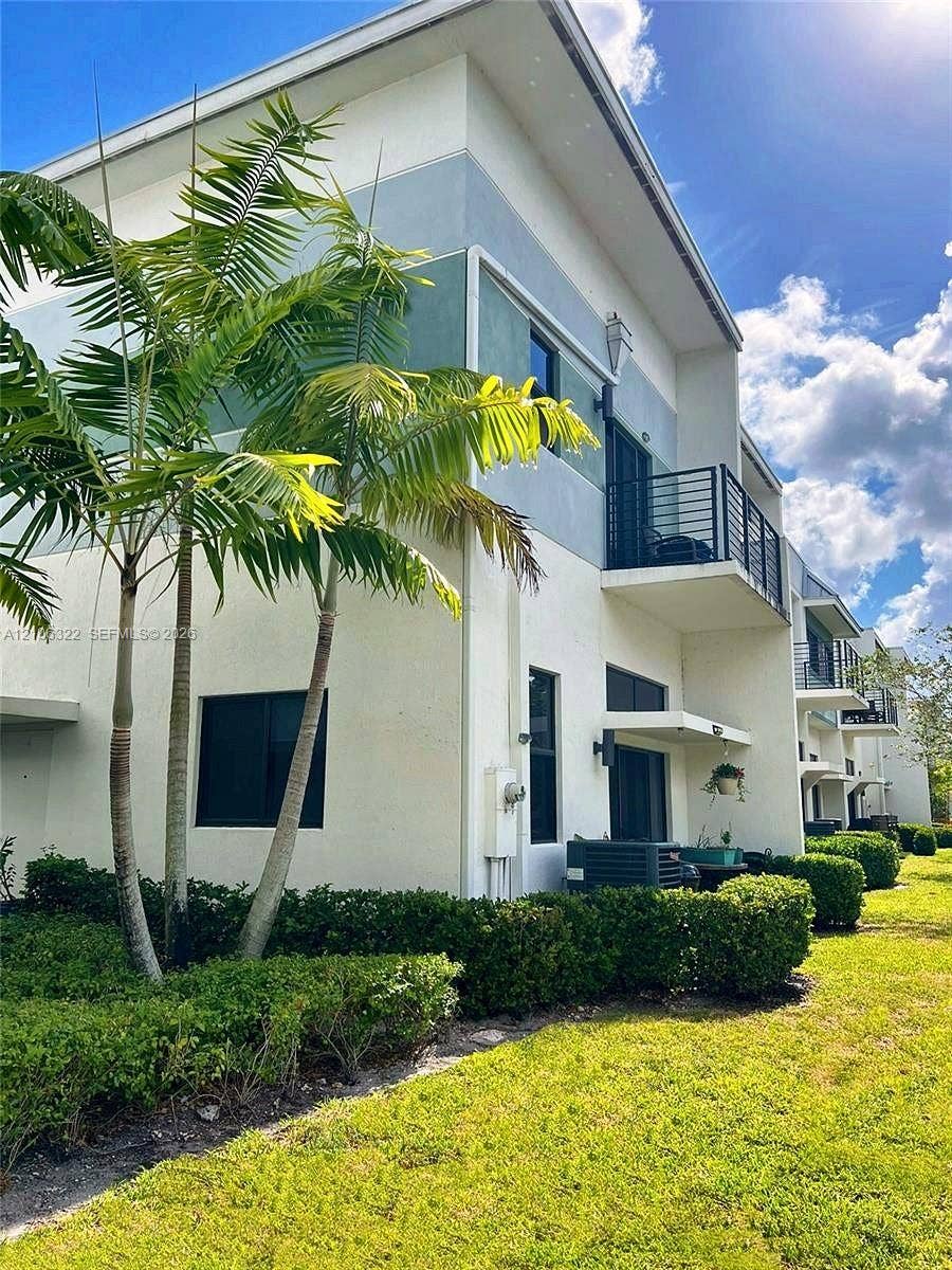 Contemporary multi-level exterior featuring smooth stucco siding, private balconies with metal railings, and integrated landscape hedging
