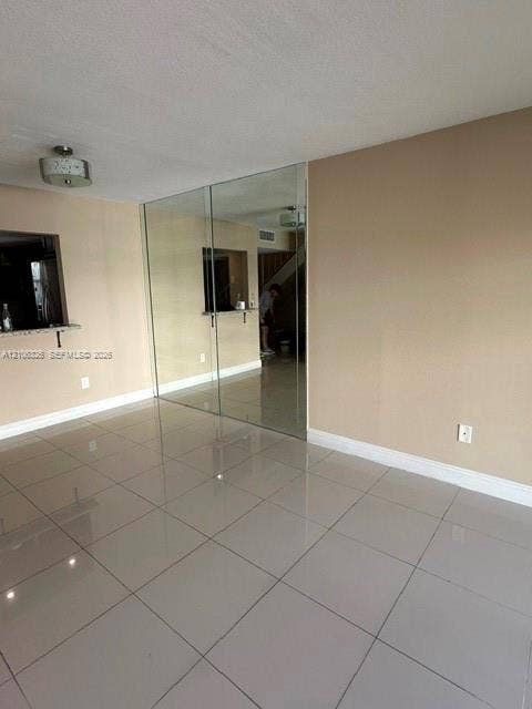 220 NW 87th Avenue, #K212, Miami, Miami, FL 33172 Neutral tile flooring, large floor-to-ceiling mirror panel, pass-through opening with stone-finish ledge, and contemporary drum-style ceiling lighting