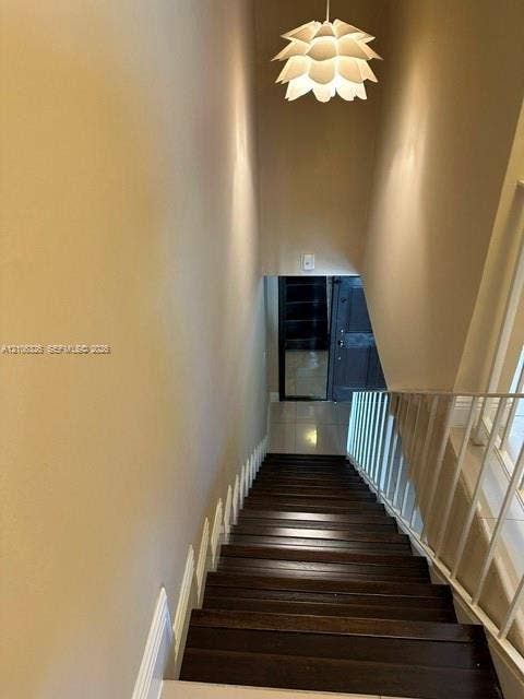 220 NW 87th Avenue, #K212, Miami, Miami, FL 33172 Staircase featuring wood-finish treads, white metal railing, and a tiered petal-style pendant light fixture