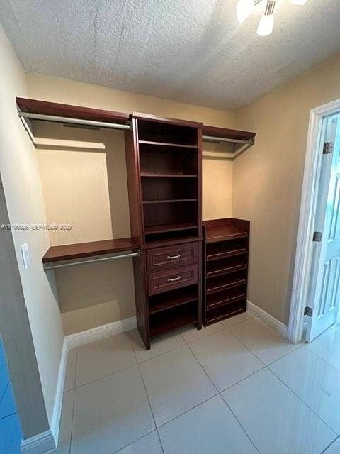 220 NW 87th Avenue, #K212, Miami, Miami, FL 33172 Walk-in closet featuring custom built-in dark wood cabinetry, two storage drawers, integrated shelving, tiered shoe storage, and ceramic tile flooring